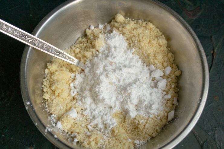 Mixing ground almond flour with powdered sugar in a bowl