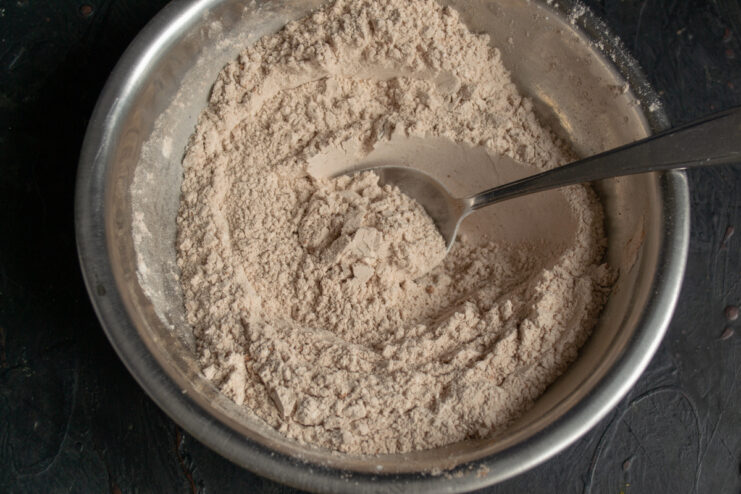 Mixing flour and cocoa powder in a metal bowl for chocolate shortbread.