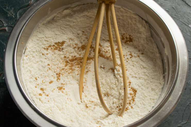 Mixing Dry Ingredients Mixing flour, powdered sugar, and ginger powder in a metal bowl