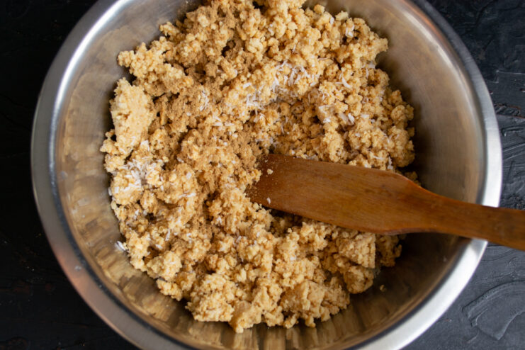 Combining dry ingredients Folding the crushed nut mixture into the buttery cookie dough in a bowl