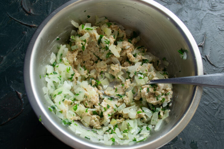 Combining the Ingredients Mixing soaked oats with sautéed onions and herbs in a bowl