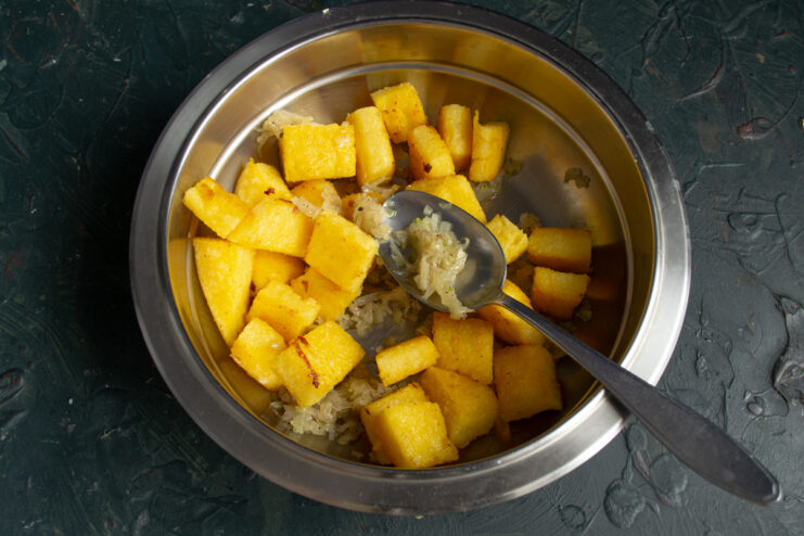 Dressing The Salad Mixing polenta with dressing in a metal bowl