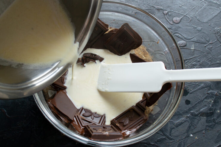 Combining the ganache base Gently folding warm cream and butter mixture into melted dark chocolate to create a smooth ganache