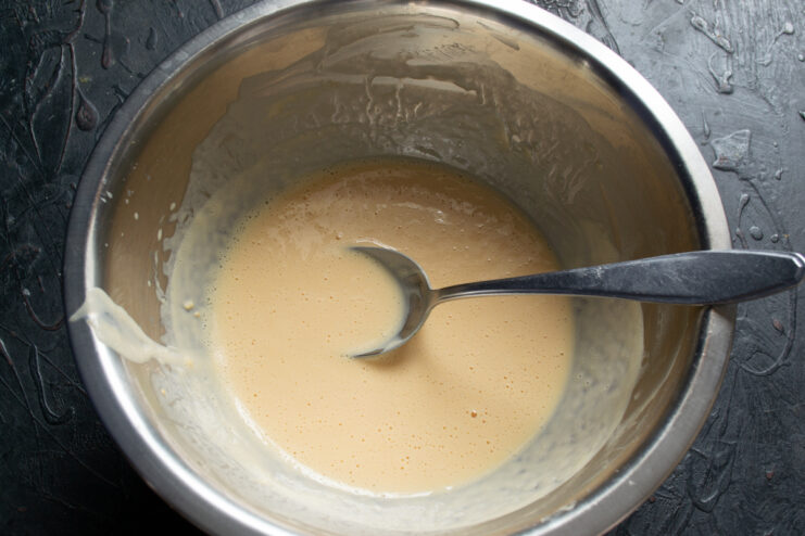 Whisking powdered eggs with milk and water in a metal bowl