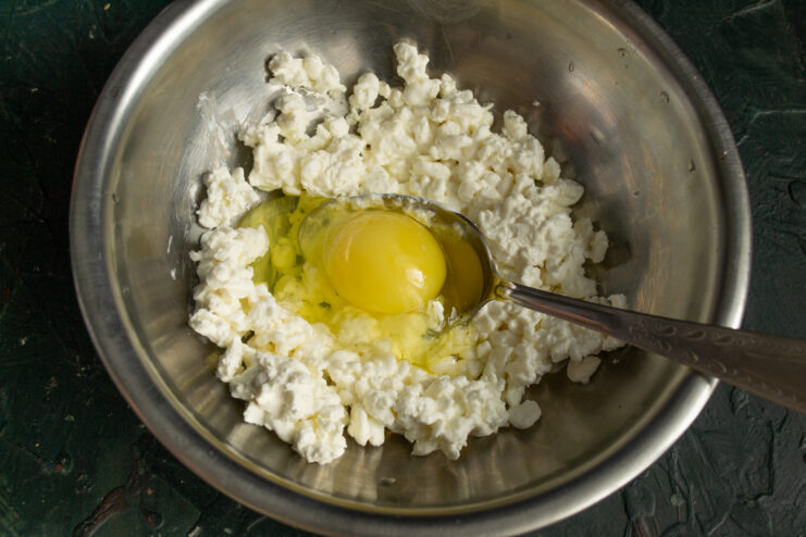 Mixing cheese and egg Mixing grainy cottage cheese with an egg in a glass bowl
