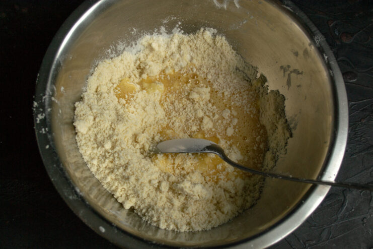 Combining dough components Mixing the sweet egg yolk mixture into the buttery crumbs