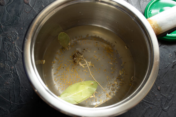 Preparing the spiced marinade Spices and herbs simmering in a saucepan to make the pickling marinade