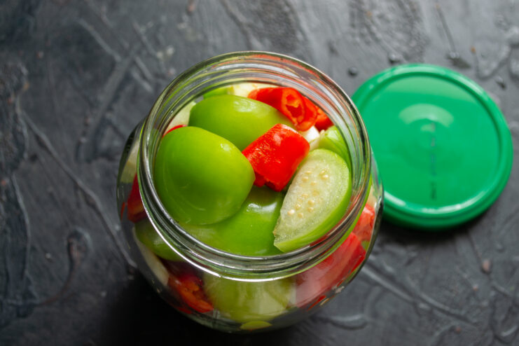 Packing the jar with vegetables Glass jar packed with colorful layers of physalis, chili, and garlic