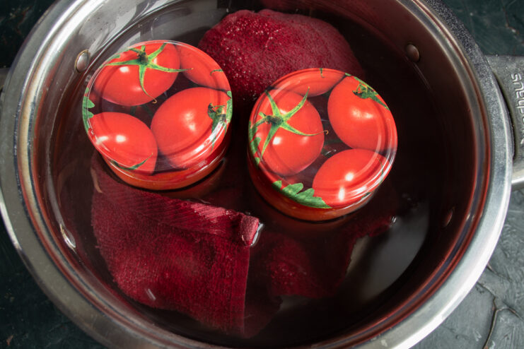 Processing jars in a boiling water bath Sterilizing sealed jars of tomatoes in a pot of boiling water