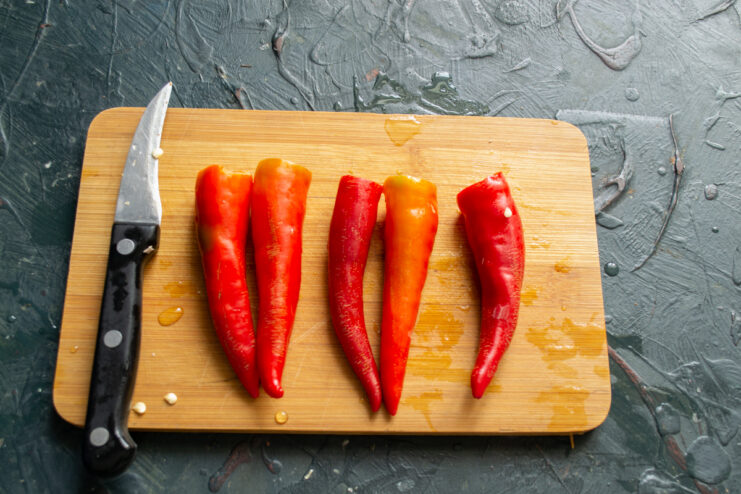Prepping Chili Peppers Trimmed red chili peppers with exposed seeds on a wooden cutting board.