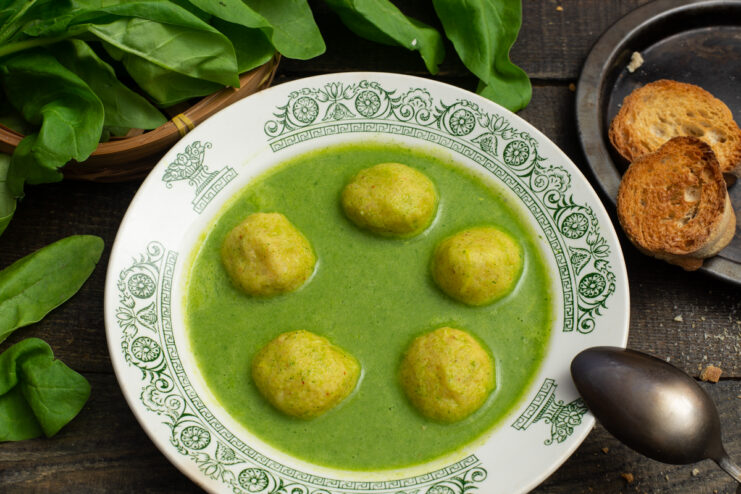 Vibrant spinach cream soup with tender rice dumplings in a bowl