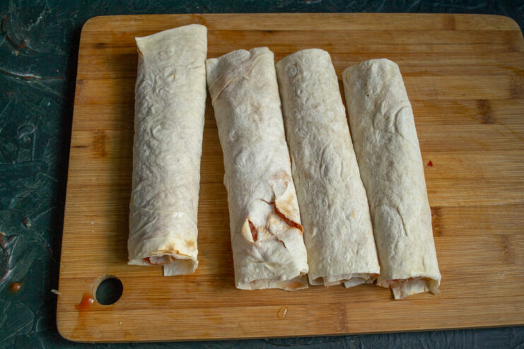 Tightly rolling the lavash flatbread to secure the meat filling