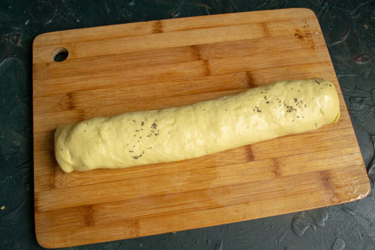 Forming the Roll Tightly rolled dough log with poppy seeds on a board