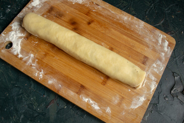 Rolling the Dough Rolled dough log with poppy seed filling resting on a wooden board