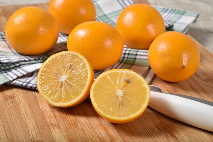 Halved Meyer Lemons Whole and halved fresh Meyer lemons resting on a wooden cutting board