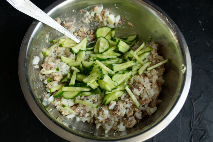 Adding fresh cucumbers Fresh cucumbers cut into julienne strips in a bowl with salad ingredients