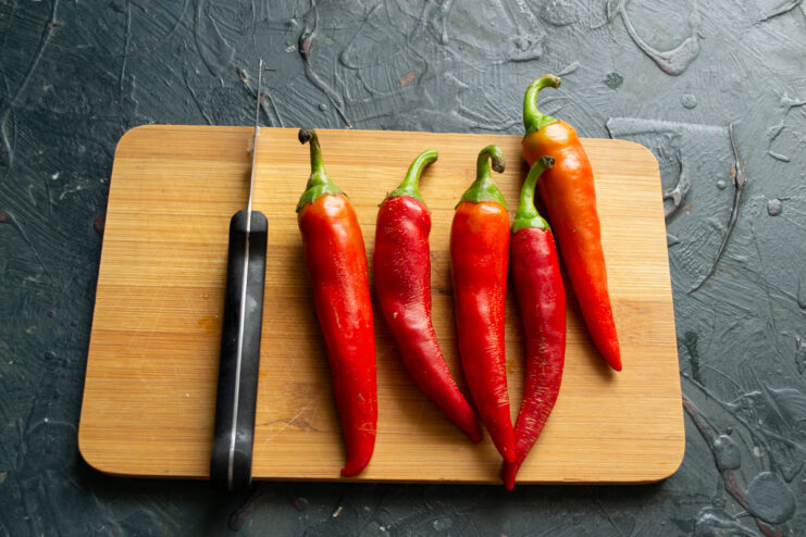 Selecting Chili Peppers Fresh red hot chili peppers laid out on a rustic wooden board.