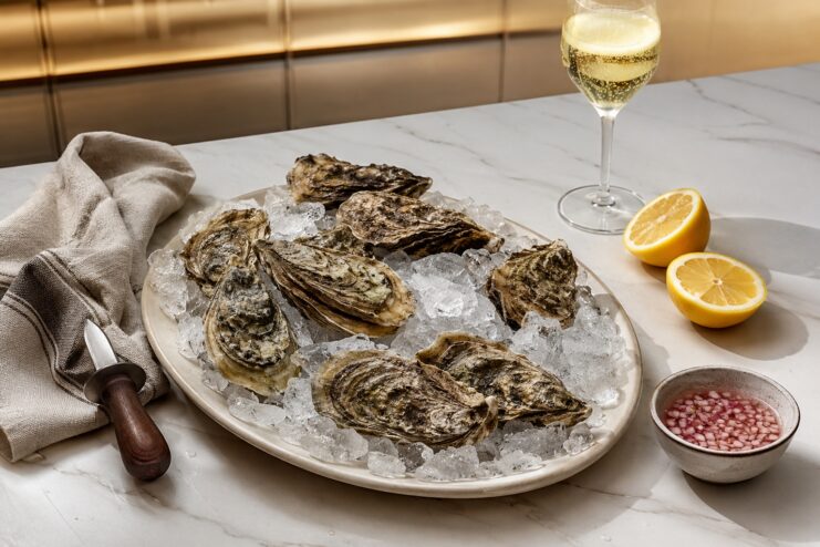 Ideal Oyster Presentation At Home Fresh oysters on ice with lemon halves and a glass of white wine