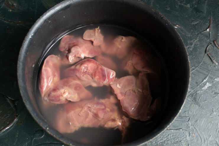 Preparing the chicken liver Raw chicken livers submerged in cold water inside a metal saucepan.