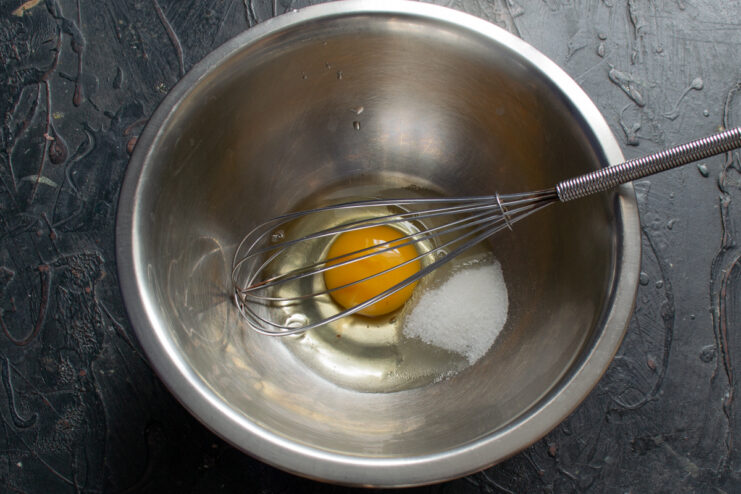 Raw egg, sugar, and salt in a mixing bowl