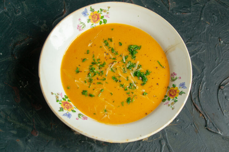 Serving the creamy soup Bowl of finished creamy fish soup topped with grated Parmesan and fresh herbs