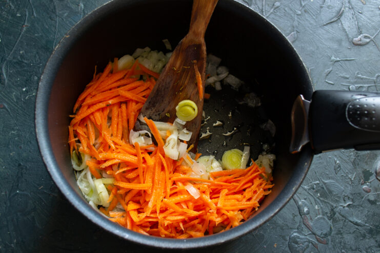 Adding the carrots Grated carrots mixed with sautéed onions in a pot
