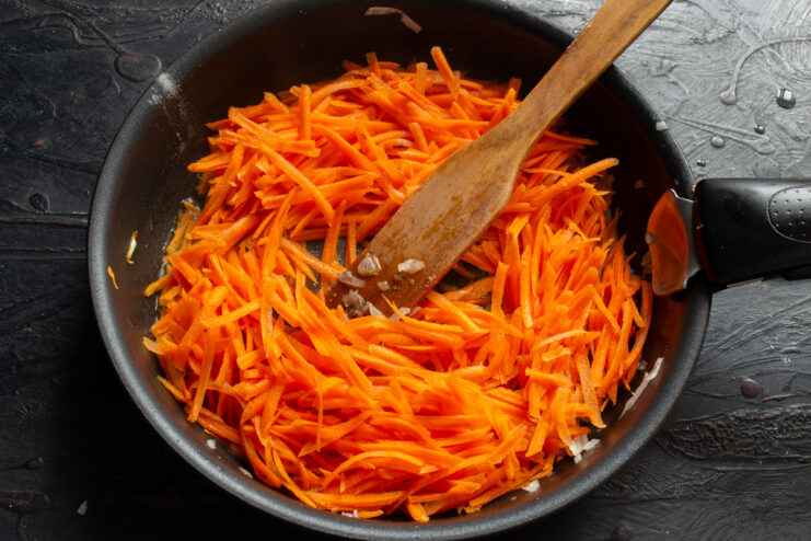 Sautéing the carrots Grated carrots sautéing in a skillet separately from other vegetables.
