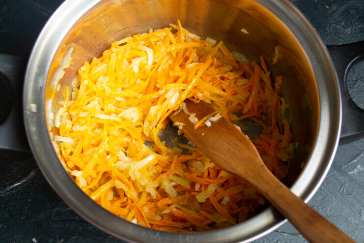 Cooking the grated carrots Grated carrots cooking alongside diced onions in a pot
