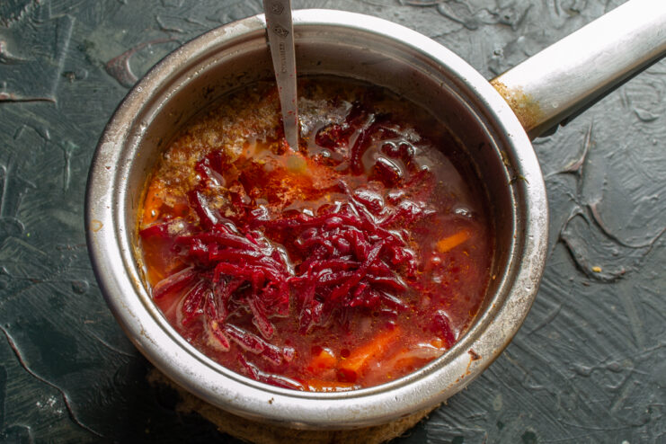 Folding In the Beets Grated braised beets being stirred into a pot of soup.