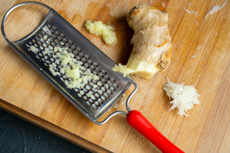 Mincing Ginger and Garlic Freshly grated ginger root and minced garlic on a wooden cutting board