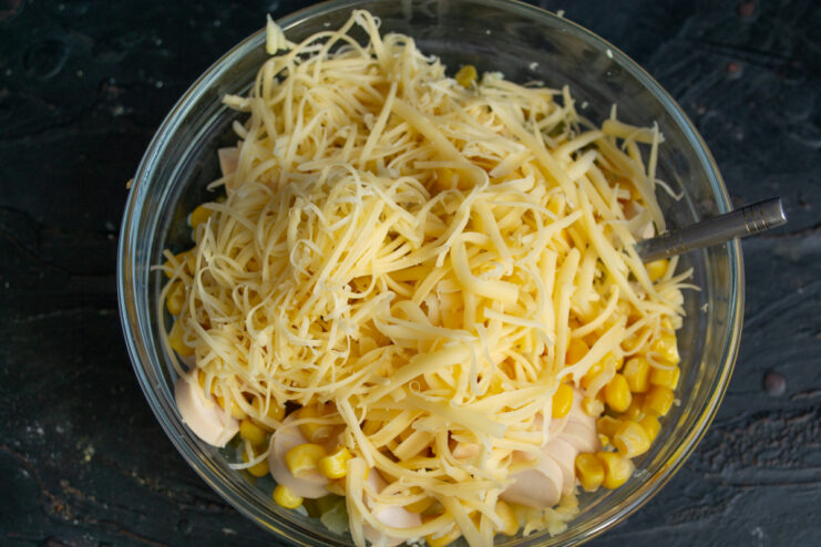Adding grated cheese Finely grated hard cheese in a bowl with salad ingredients.