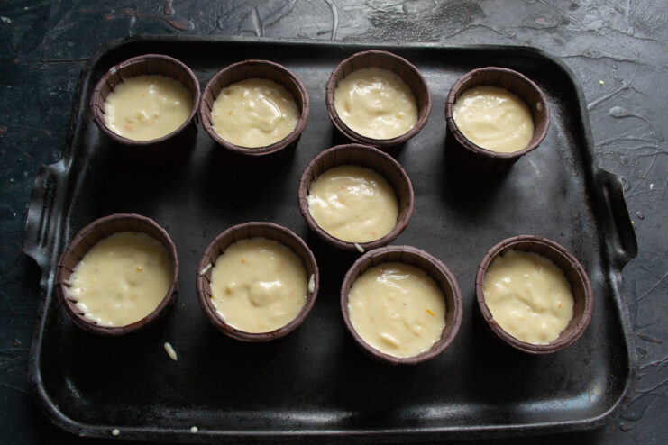 Portioning the batter into molds Muffin batter portioned into paper liners inside a baking pan