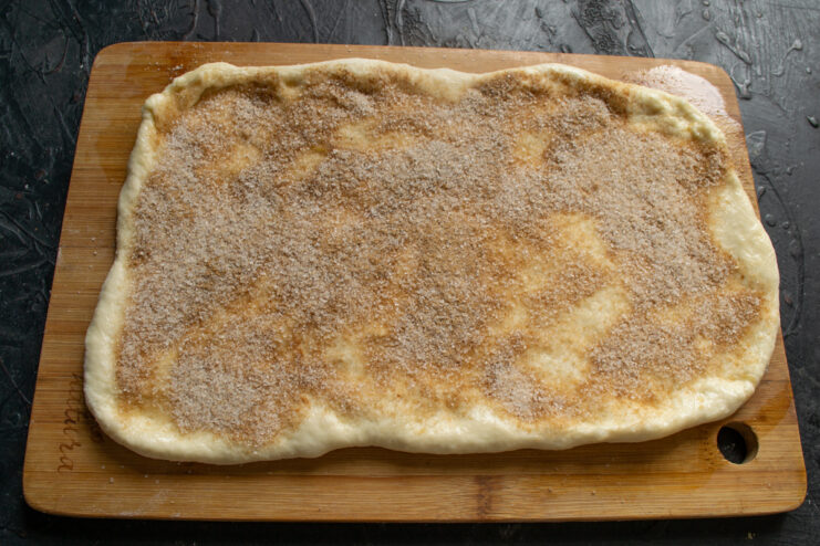 Spreading butter and spices Brushing rolled dough with melted butter and sprinkling a cinnamon sugar mixture