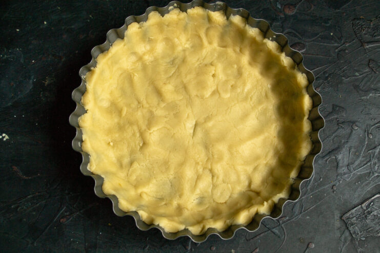 Forming the crust in the pan Pie dough pressed into a baking pan with raised edges