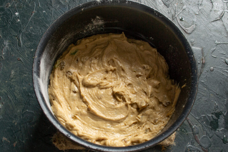 Cake batter spread evenly inside a round baking pan