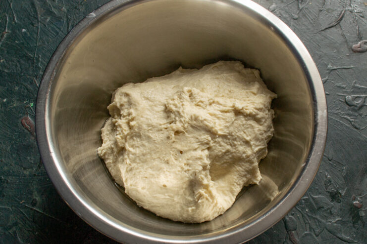 Bread dough resting in an oiled metal bowl