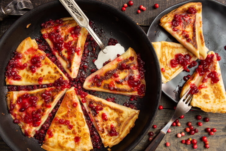 Thin milk crepes served with vibrant lingonberry jam