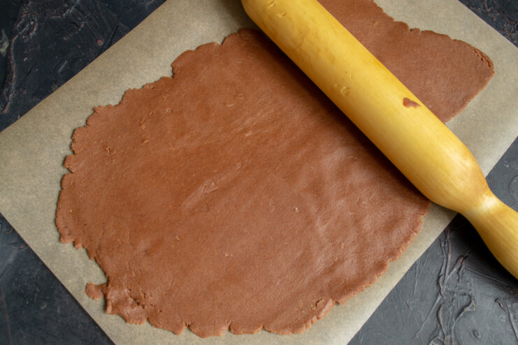 Thinly rolled chocolate dough on parchment paper.