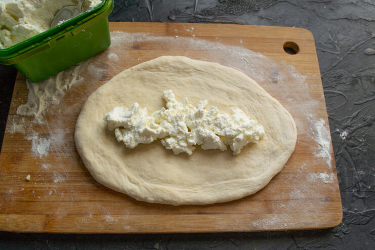 Spooning sweet farmers cheese filling onto the center of rolled dough