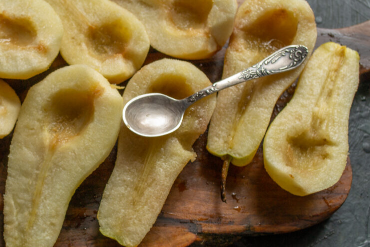 Processing the Fruit Removing the core and seeds from pear halves using a small spoon