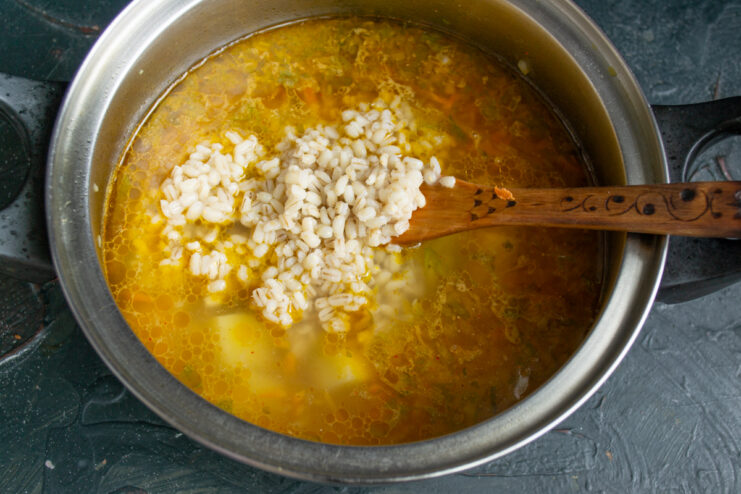 Adding cooked pearl barley Adding cooked fluffy pearl barley into the simmering soup pot