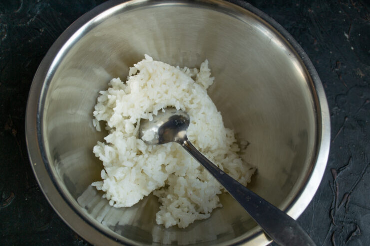 Preparing rice for the salad Cooked white short-grain rice in a metal mixing bowl