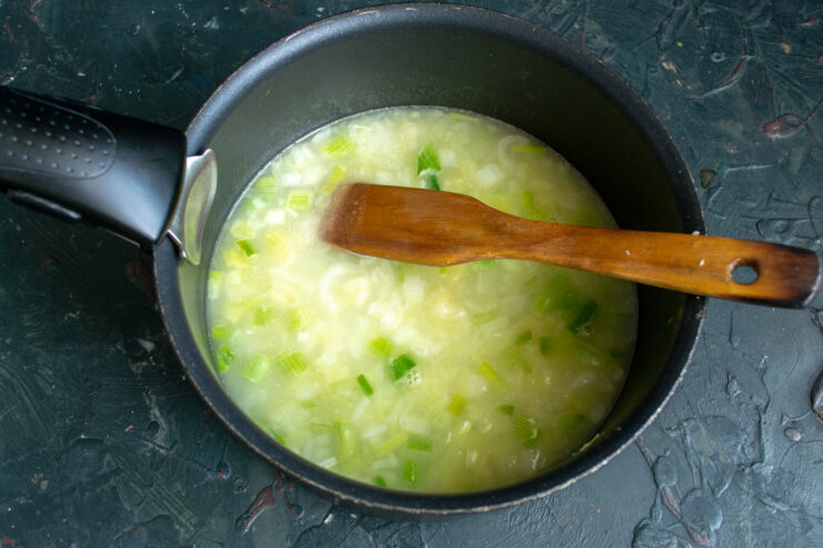 Pouring broth into the pot while whisking constantly