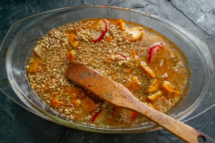Adding water Water being poured into the baking dish with farro and meat