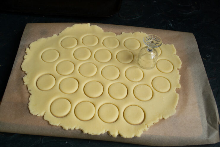 Cutting The Cookies Cutting small circles out of rolled dough using a thin-rimmed shot glass