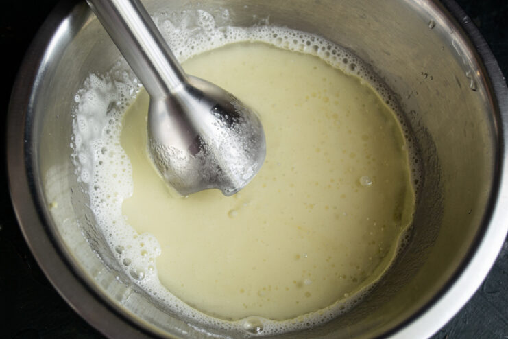 Fluffy whisked egg and sugar mixture in a metal mixing bowl