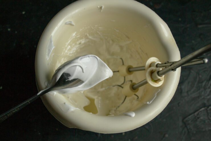 Whipping the egg whites Egg whites whipped to stiff glossy peaks in a glass bowl