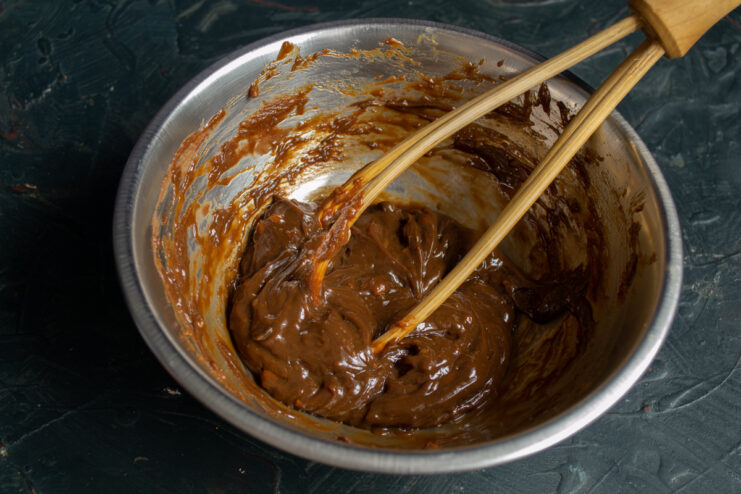 Whisking the chocolate cream until smooth Whisking thick chocolate buttercream until smooth and glossy