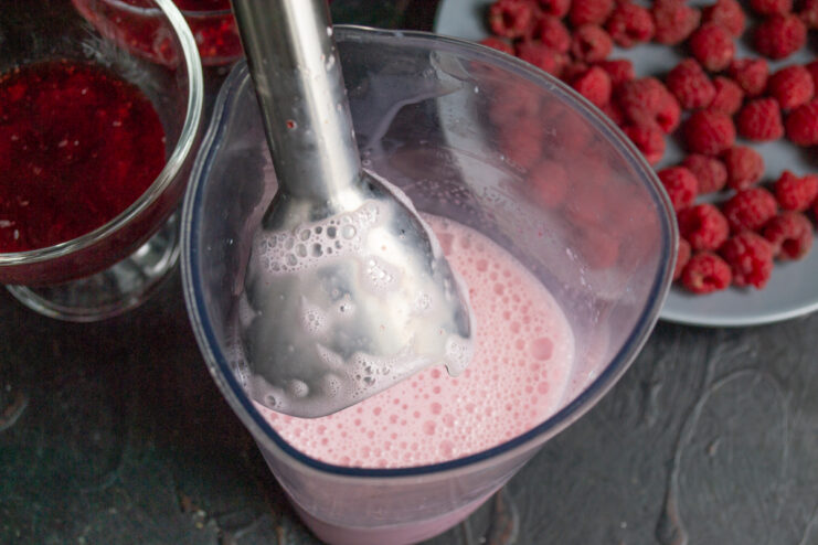 Whisking the Milk Layer Blending the milk mixture with an immersion blender in a tall beaker