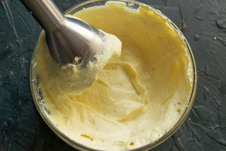 Blending the dressing Blending the dressing with an immersion blender in a clear bowl